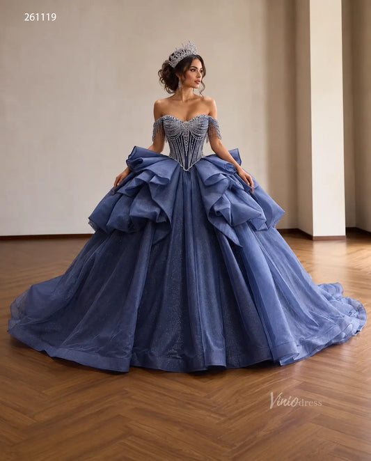Dusty blue quinceañera dress with crystal-draped corset, off-shoulder straps, and a voluminous ruffled skirt.