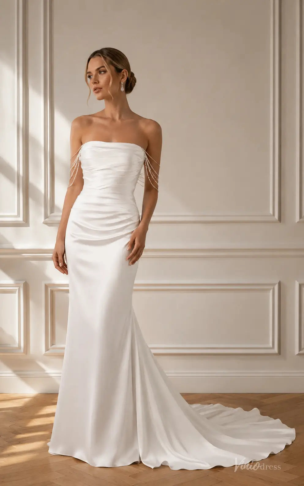 Strapless white satin mermaid wedding dress featuring a ruched bodice and delicate pearl-draped shoulder straps.