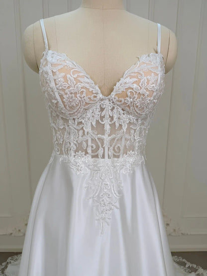 White satin wedding dress with a sheer lace appliqué bodice and sweetheart neckline on a mannequin.