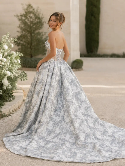 Dusty blue jacquard wedding dress with a strapless corset bodice and a voluminous floor-length ball gown skirt.