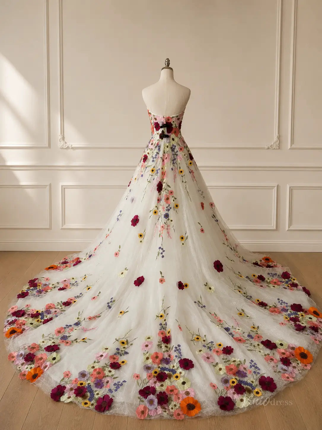 Strapless white A-line wedding dress featuring a long train adorned with colorful 3D floral appliqués and glitter tulle.