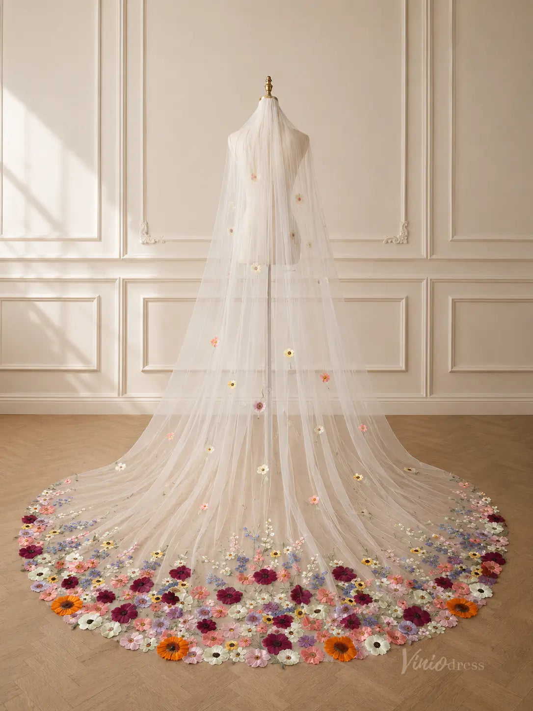 Long ivory tulle wedding veil featuring scattered 3D floral appliqués and a dense, colorful wildflower hem design.