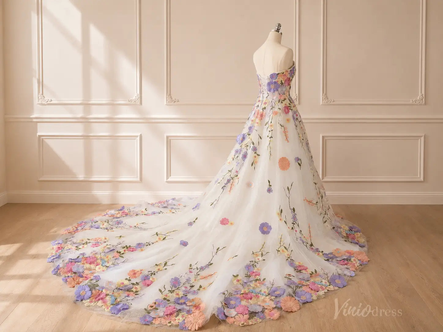Strapless white A-line wedding dress with a long train, featuring colorful 3D floral appliques and delicate vine embroidery.