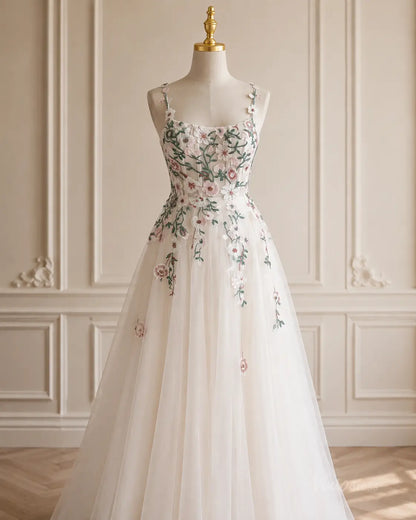 A-line tulle wedding dress with delicate floral embroidery, spaghetti straps, and a sweetheart neckline on a mannequin.