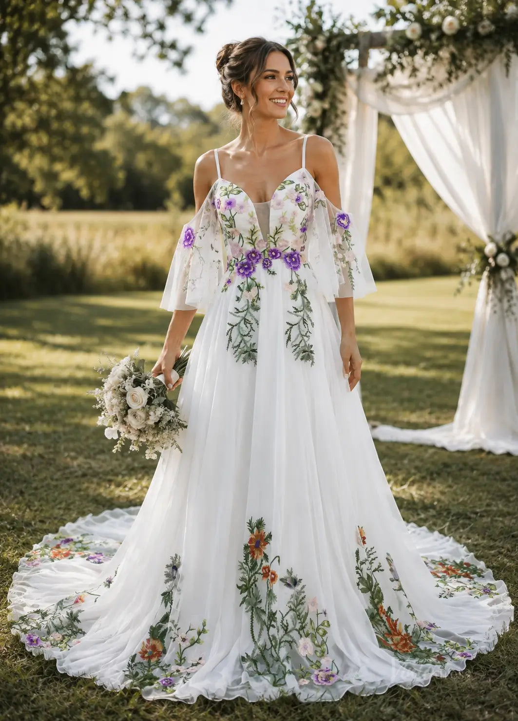 White pleated chiffon wedding dress with cold-shoulder sleeves and colorful floral embroidery in a garden setting.