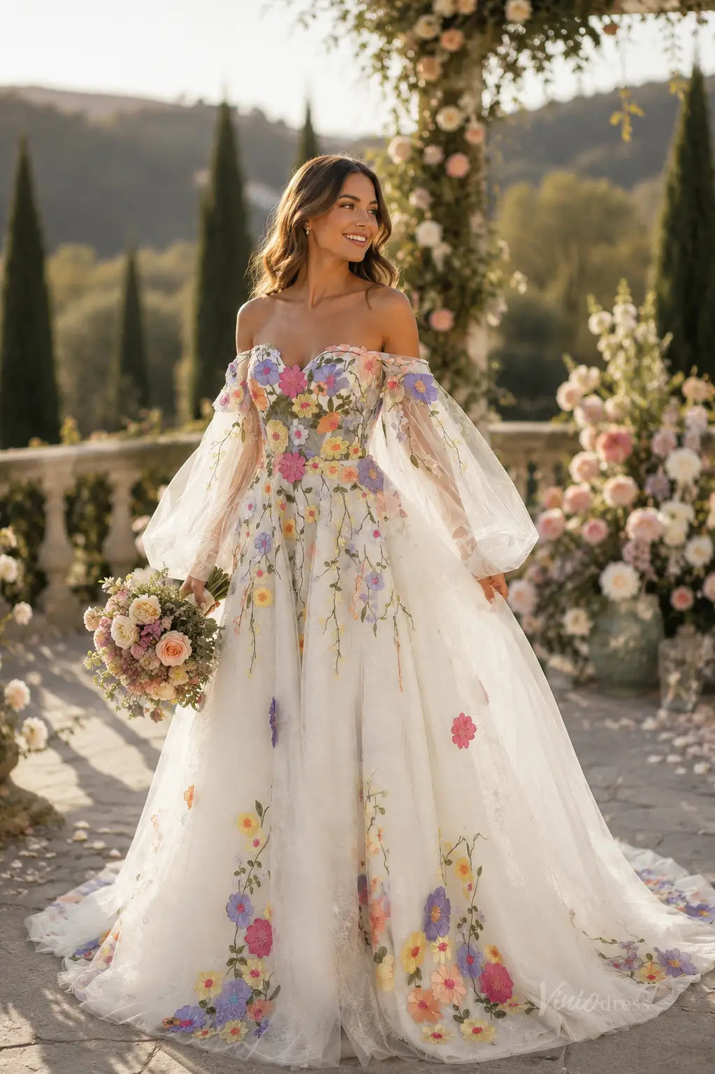 Off-the-shoulder A-line wedding dress in white tulle with colorful 3D floral embroidery and sheer puff sleeves.