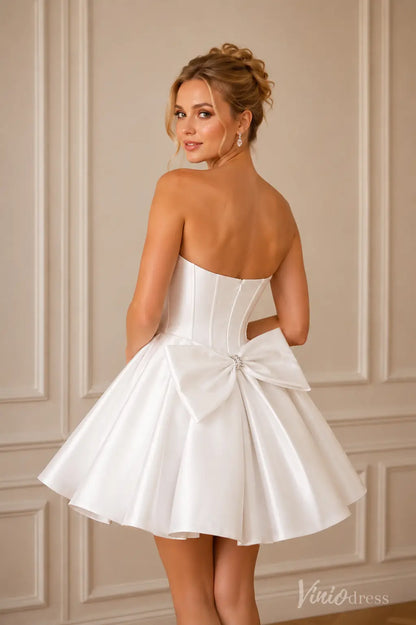 Short white strapless satin dress with a corset back and a large bow detail.