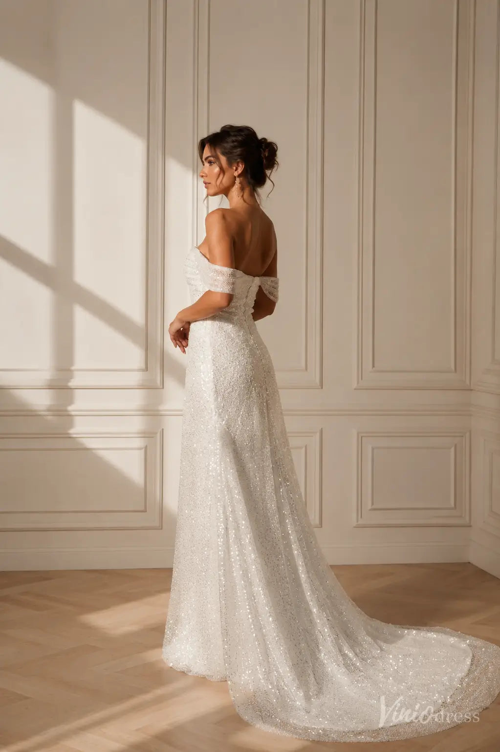 White off-the-shoulder wedding dress with a sequined A-line silhouette and a graceful train.