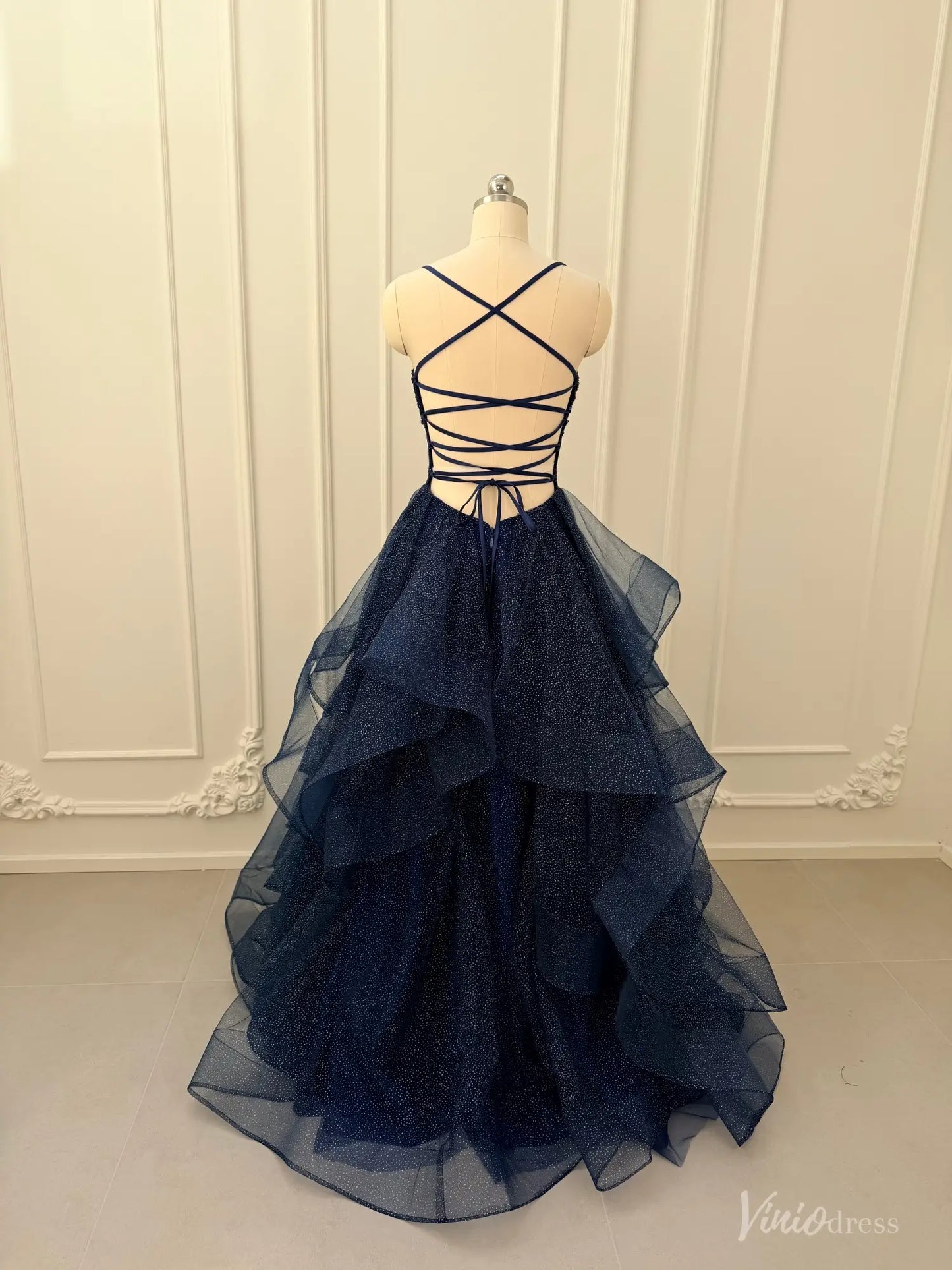Navy blue glitter tulle ball gown with a lace-up corset back and dramatic tiered ruffle skirt on a mannequin.