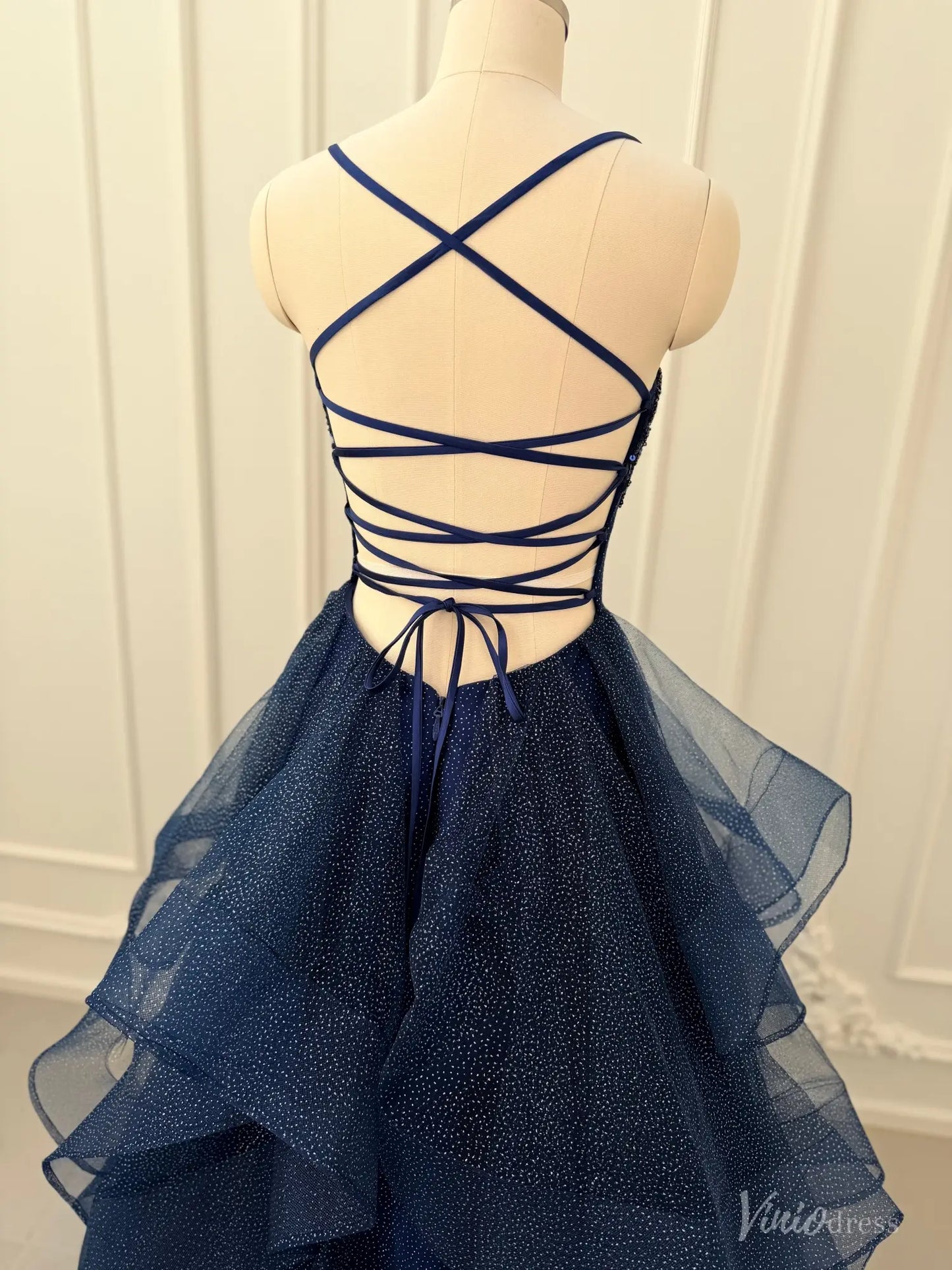 Navy blue glitter tulle prom dress with a lace-up corset back and tiered ruffle ball gown skirt.