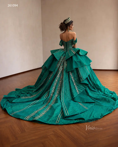 Emerald green quinceañera ball gown with gold-beaded corset, sculptural tiered peplum, and a sweeping train.
