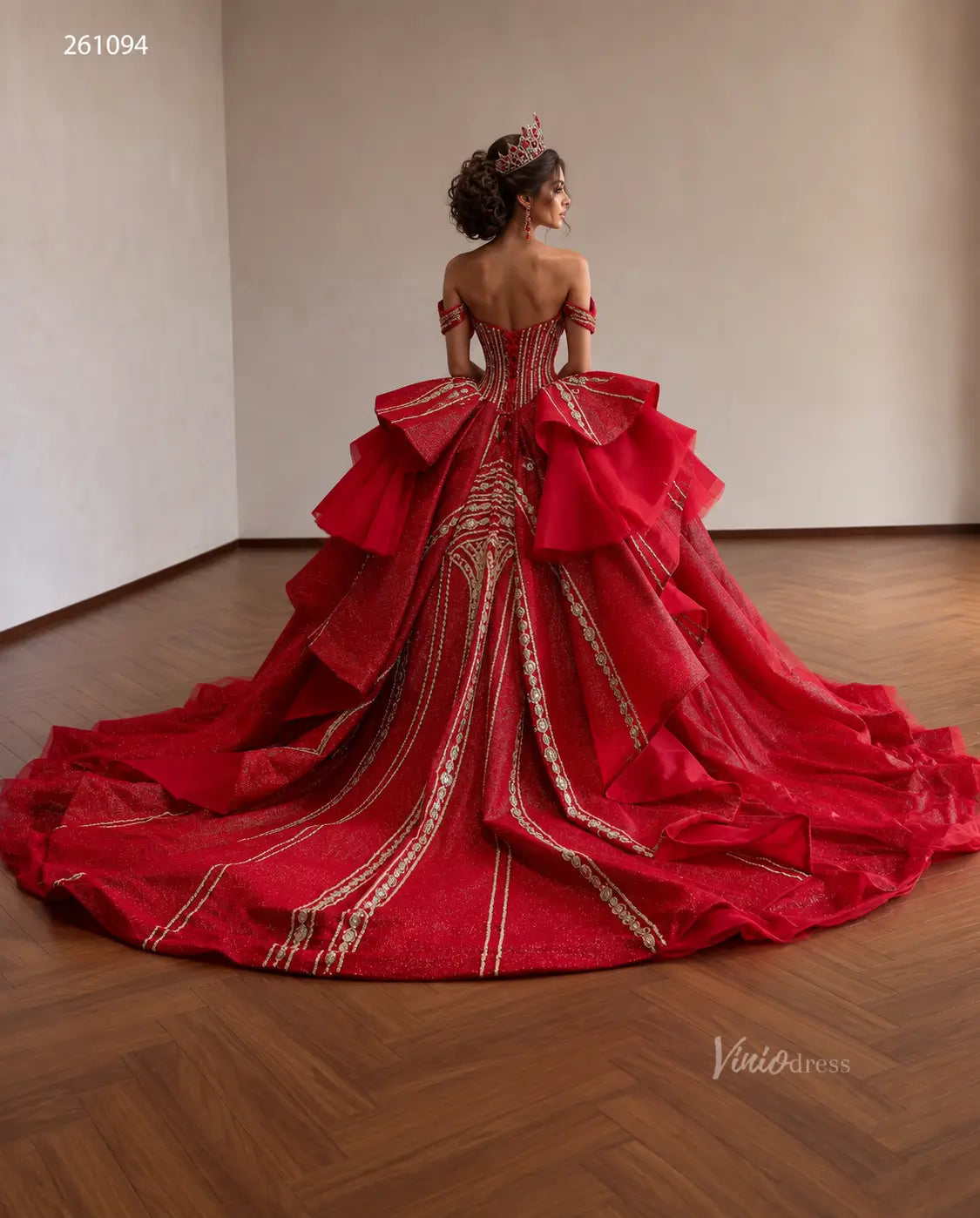 Red off-shoulder quinceañera ball gown with gold-beaded vertical patterns, sculptural tiered peplum, and sweeping train.