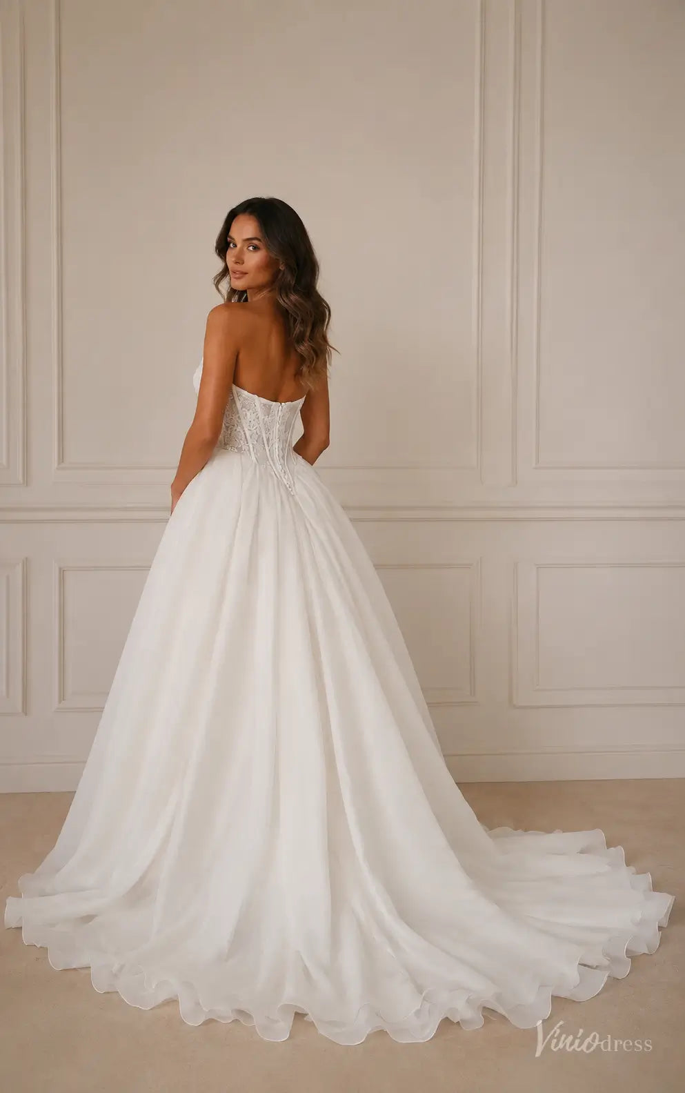 Ivory strapless ball gown wedding dress with a lace corset bodice, basque waist, and full organza chapel train.