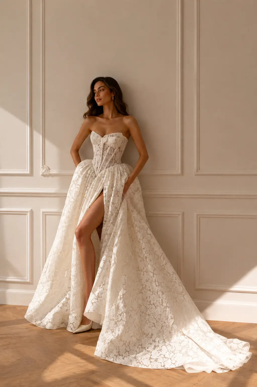 White strapless wedding dress with a corset bodice, floral lace fabric, and a high-slit full skirt.