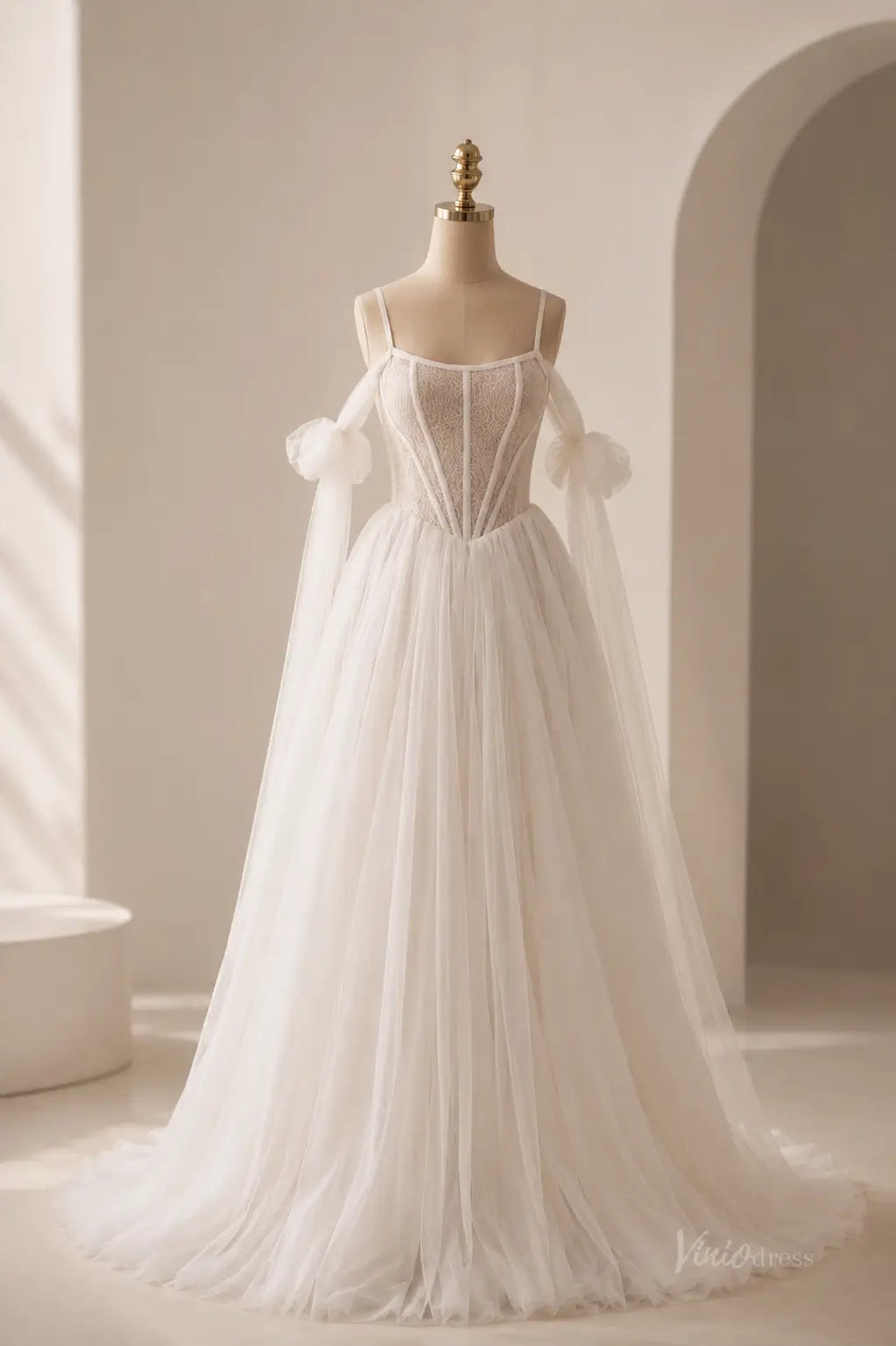 White A-line wedding dress with a lace corset bodice, spaghetti straps, and sheer detachable puff sleeves in tulle.
