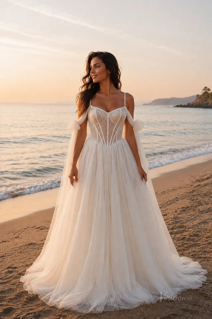 White A-line wedding dress with a lace corset bodice, spaghetti straps, and flowing tulle skirt on a beach at sunset.