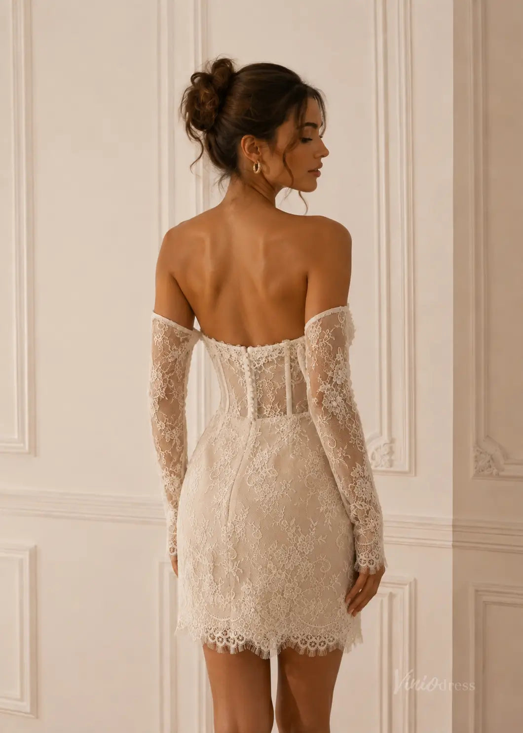 Off-the-shoulder ivory lace mini wedding dress with a corset bodice and long sheer sleeves.