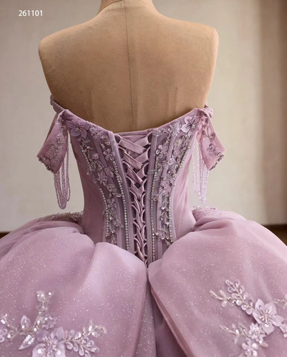 Lilac quinceañera ball gown with crystal corset, lace-up back, beaded off-shoulder drapes, and 3D floral tulle skirt.