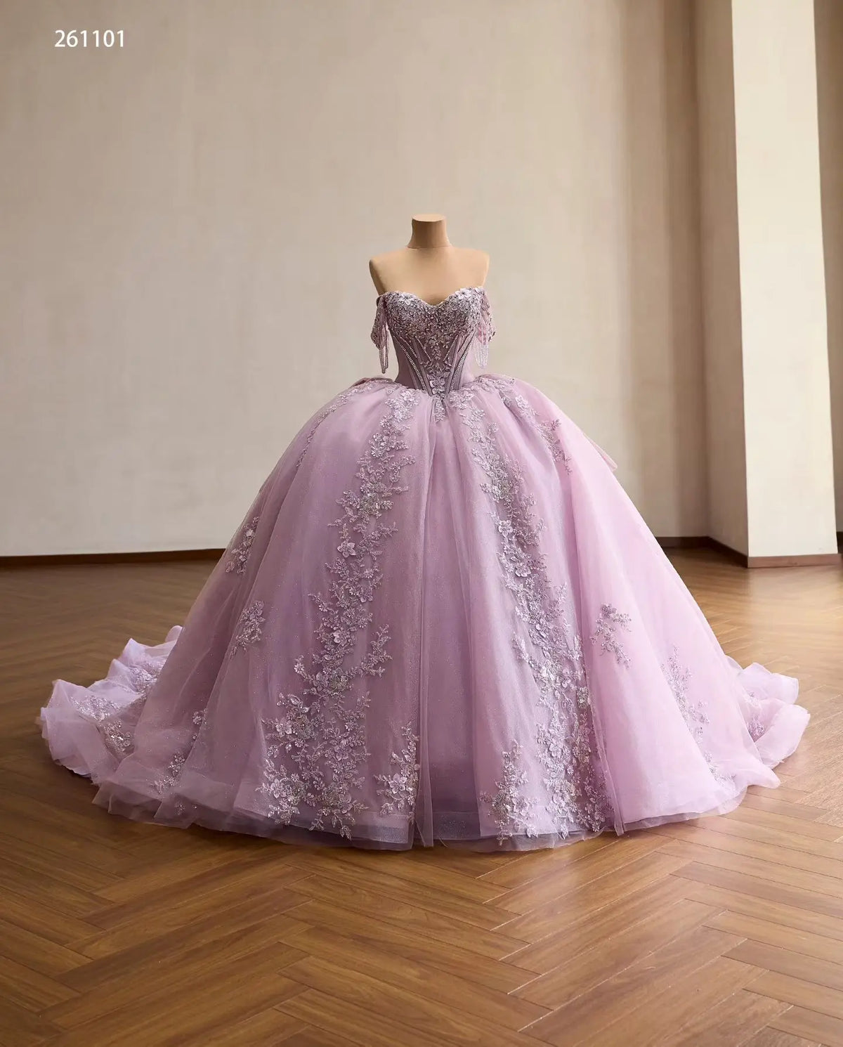 Lilac quinceañera ball gown with crystal corset, off-shoulder drapes, and 3D floral appliqués on a full tulle skirt.