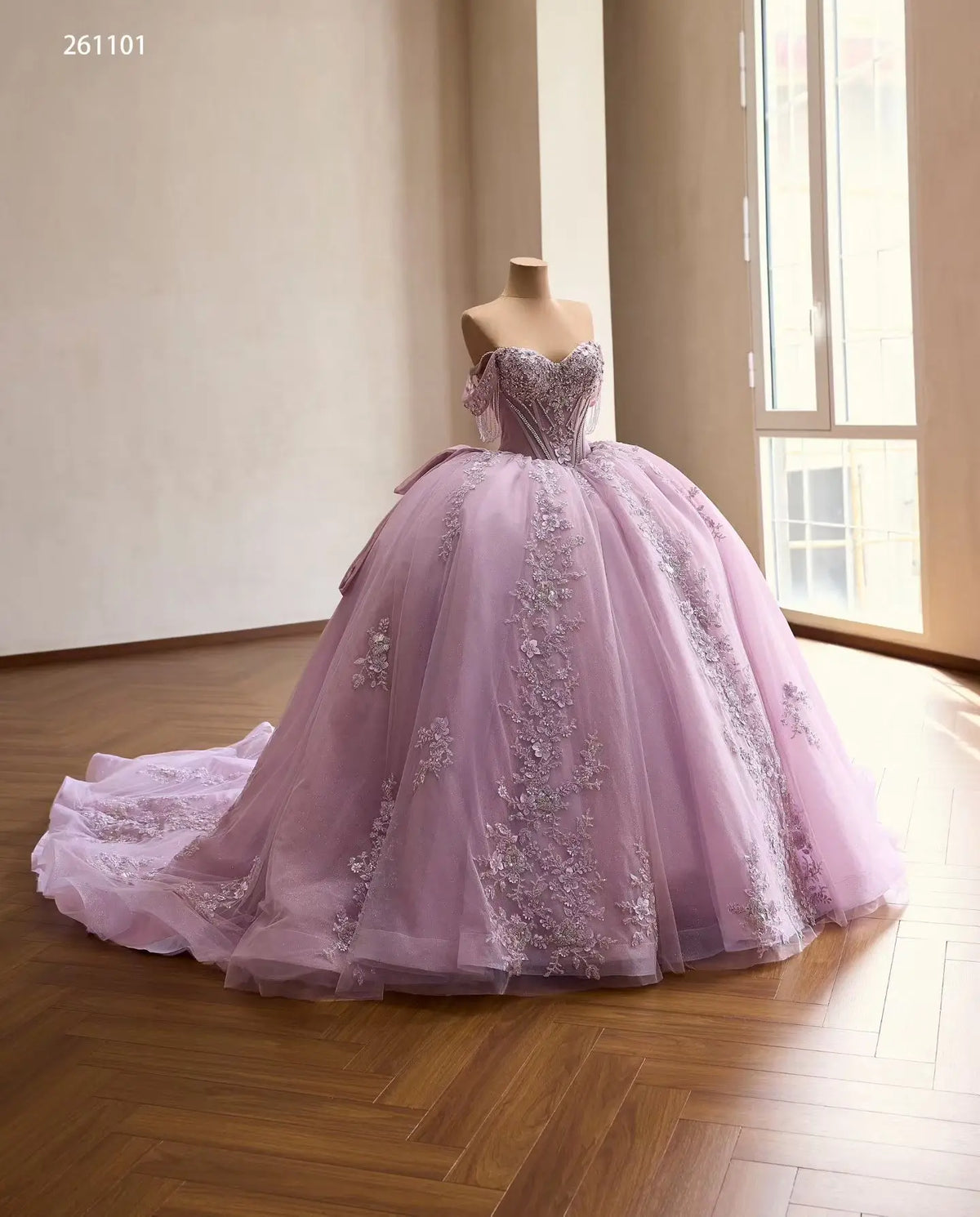 Lilac off-shoulder quinceañera ball gown with crystal corset, 3D floral appliqués, and a full tulle skirt with train.