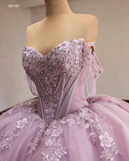 Lilac quinceanera ball gown with crystal corset, 3D floral appliqués, beaded off-shoulder drapes, and full tulle skirt.