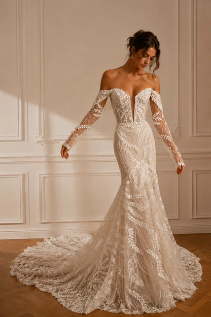 Off-the-shoulder ivory wedding dress with long sheer sleeves, plunging neckline, and intricate leaf-patterned lace embroidery.