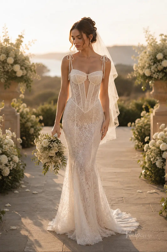 ML195 ivory lace mermaid wedding dress with a corset bodice, tie straps, and a sheer veil in a garden setting.