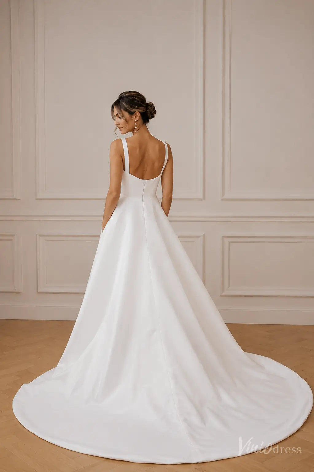 Minimalist white A-line wedding dress with a square neckline, thick straps, and a sweeping train.