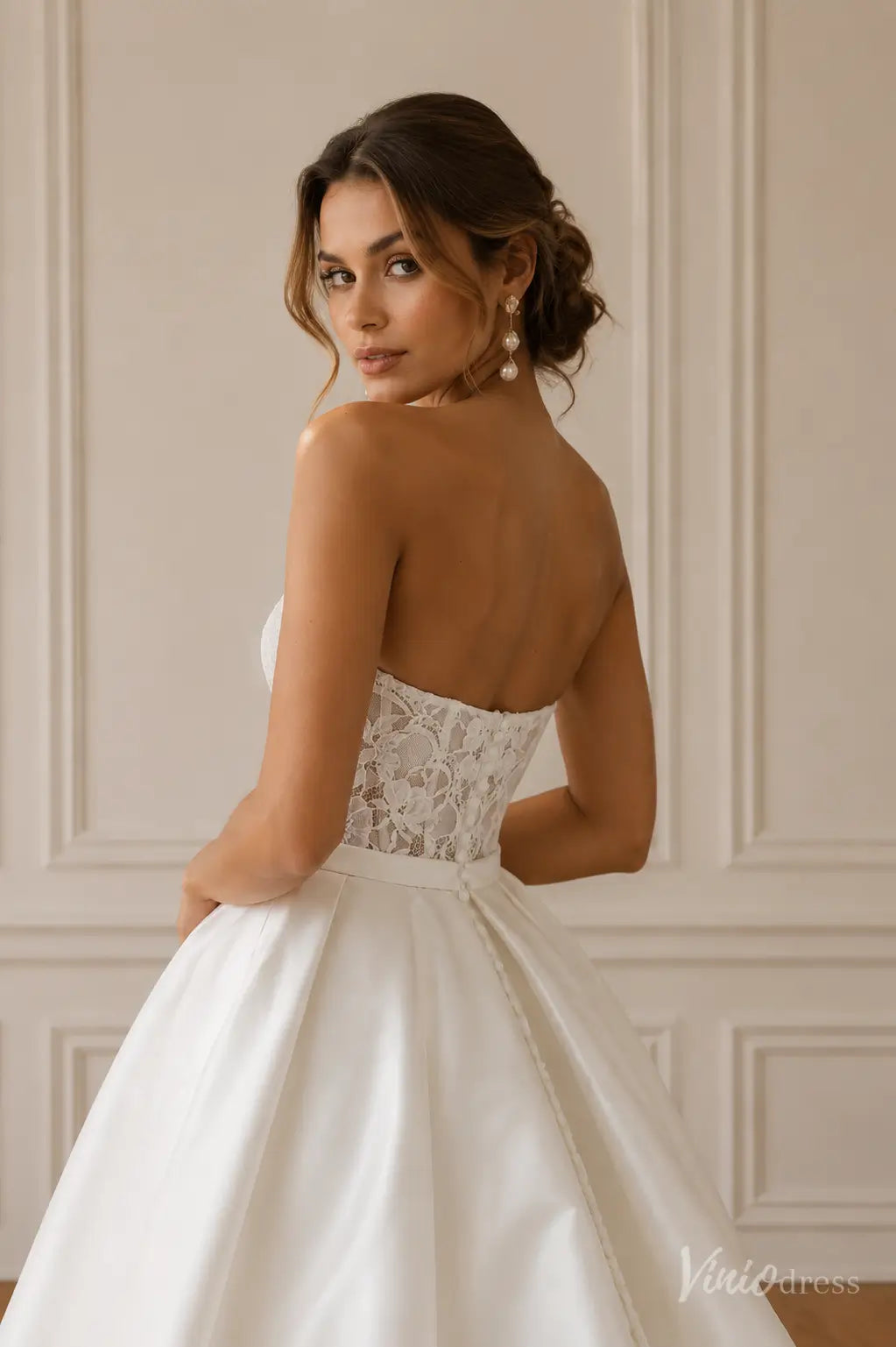 Strapless white wedding dress with a lace corset bodice and a full satin skirt featuring a button-back closure.
