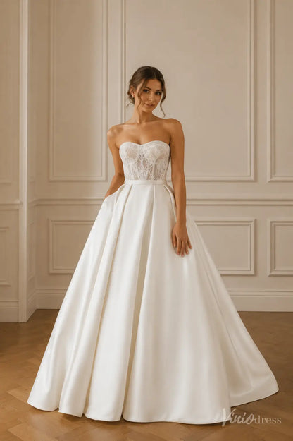 Strapless ivory wedding dress with a sheer lace corset bodice and a full, pleated satin A-line skirt.