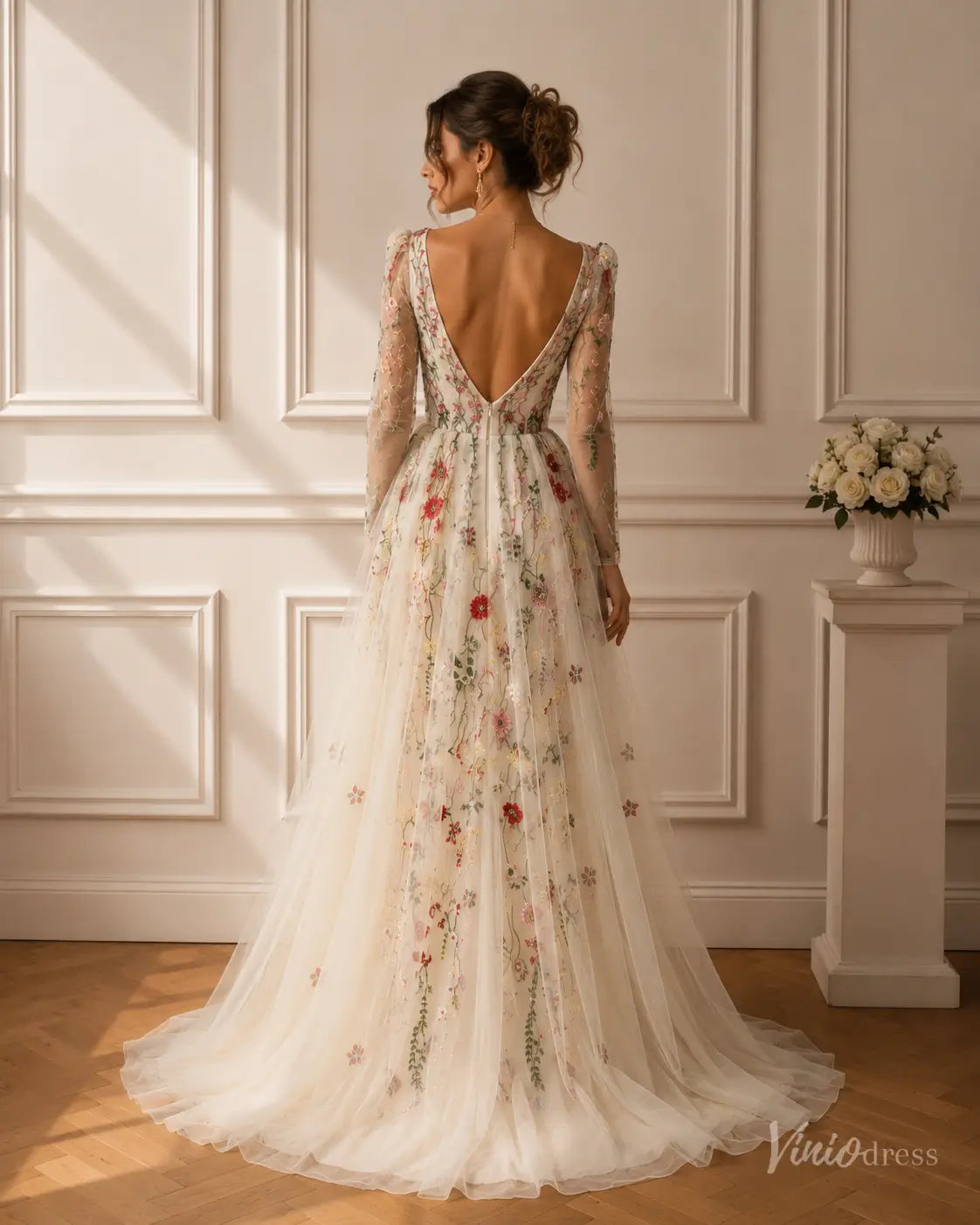 Back view of a V-neck mermaid wedding dress with long sleeves, tulle overskirt, and colorful floral embroidery.