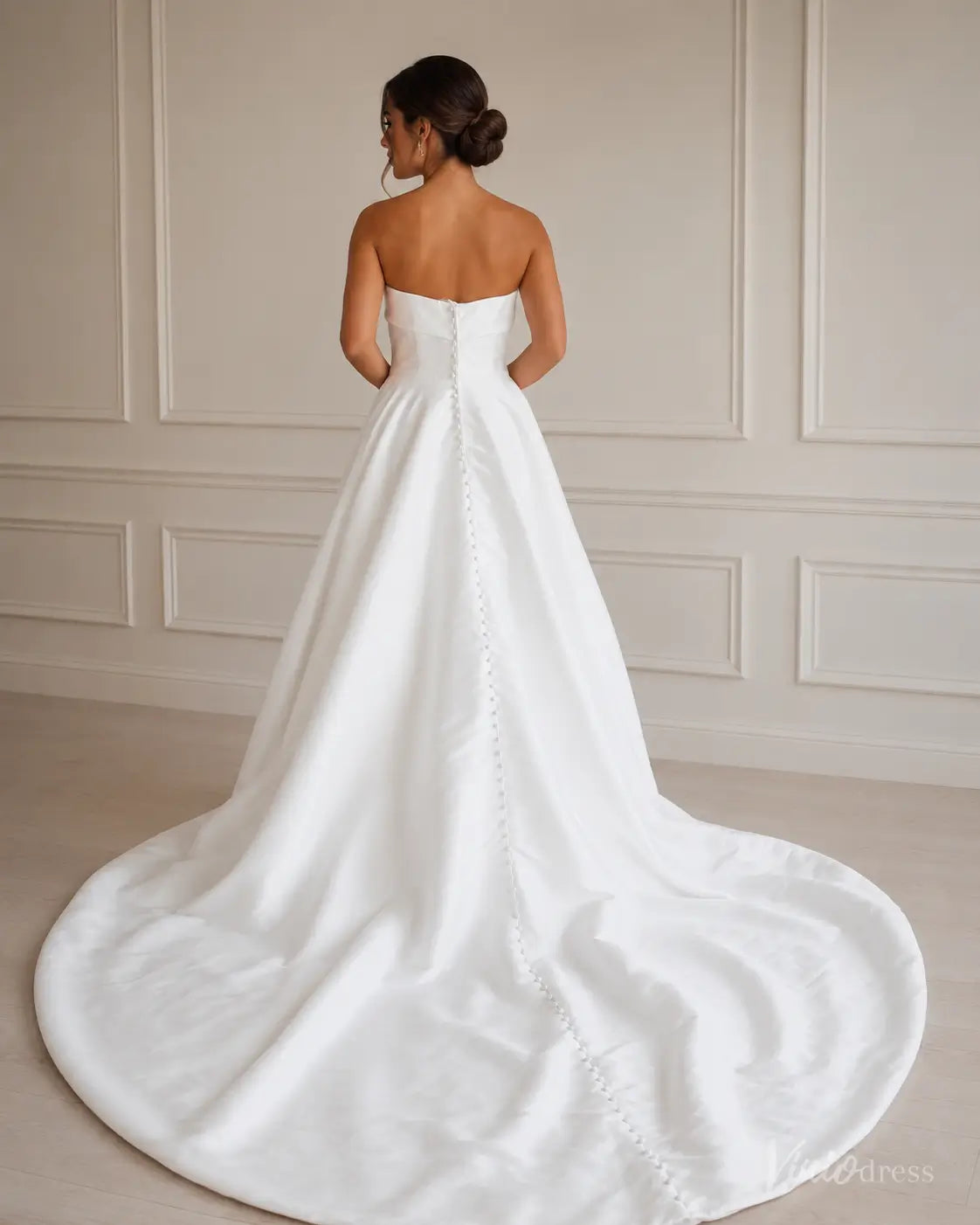 Strapless white Mikado wedding dress with a fitted bodice and a long train featuring a row of elegant fabric buttons.