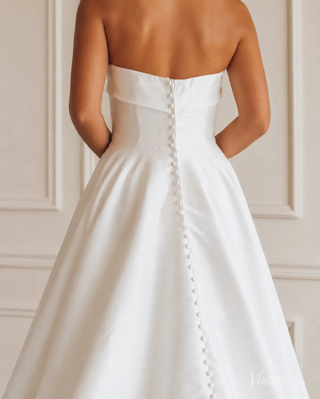 Back view of a white strapless Mikado wedding dress featuring a full A-line skirt and a row of elegant fabric buttons.