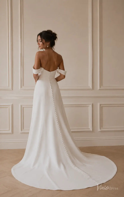 Minimalist white satin off-shoulder wedding dress with a button-back bodice and flowing chapel train.