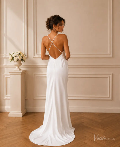 Minimalist white satin wedding dress with an open crisscross back, spaghetti straps, and a flowing floor-length skirt.