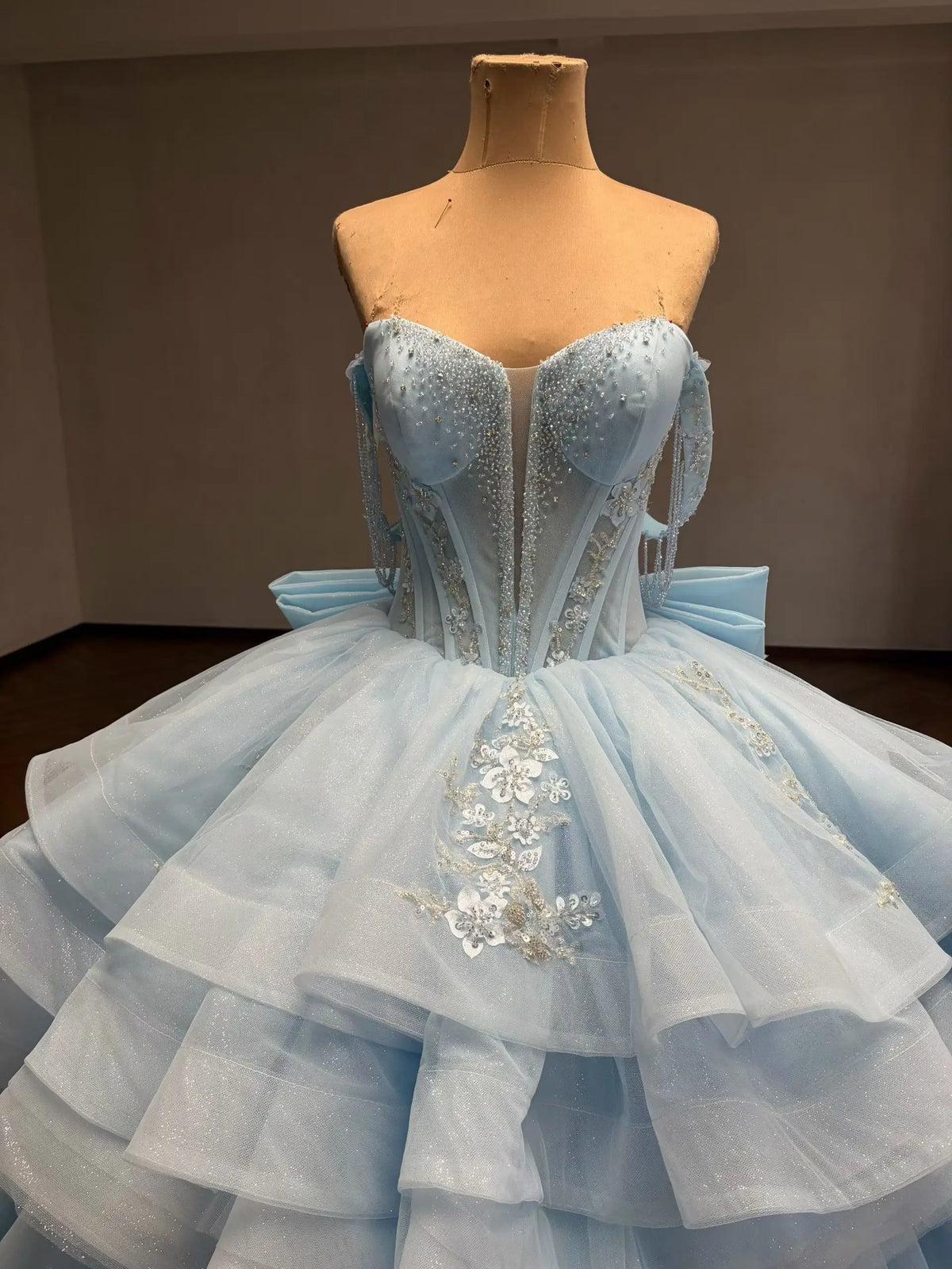 Mint green convertible quinceañera ball gown with beaded corset bodice, floral appliqué, and a detachable ruffled overskirt.