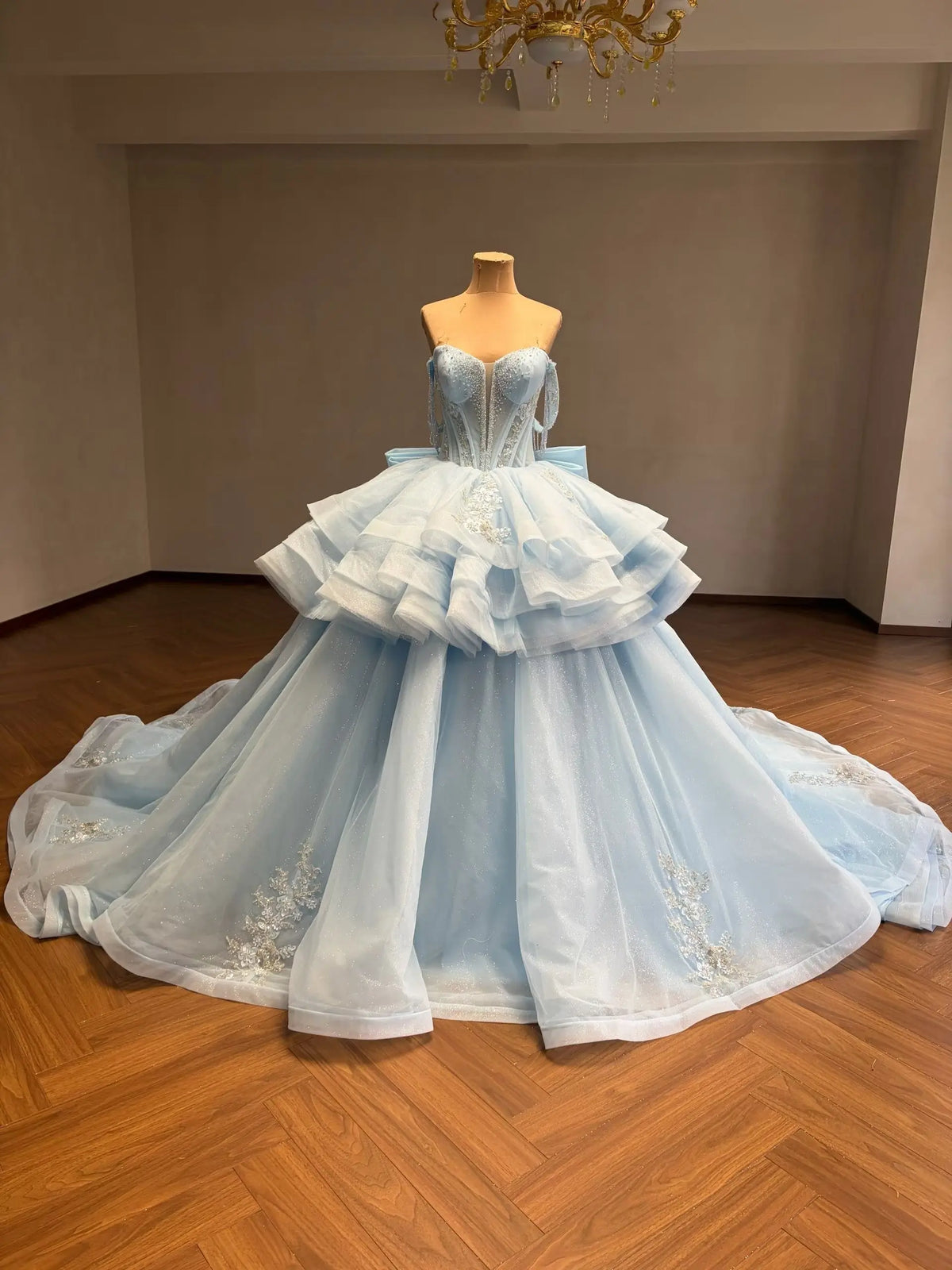 Mint green convertible quinceañera ball gown with a beaded corset bodice, tiered ruffled overskirt, and floral appliqué.