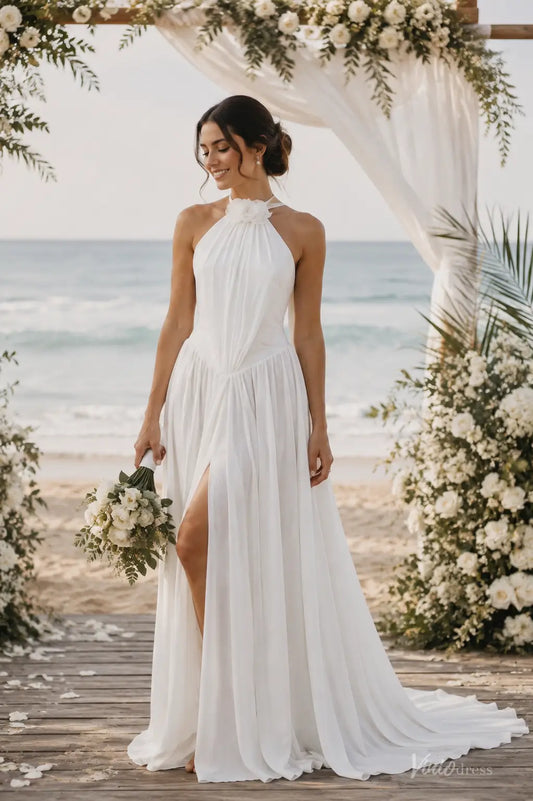 White A-line chiffon beach wedding dress with a halter neckline, floral detail, and a high side slit on a sandy shore.
