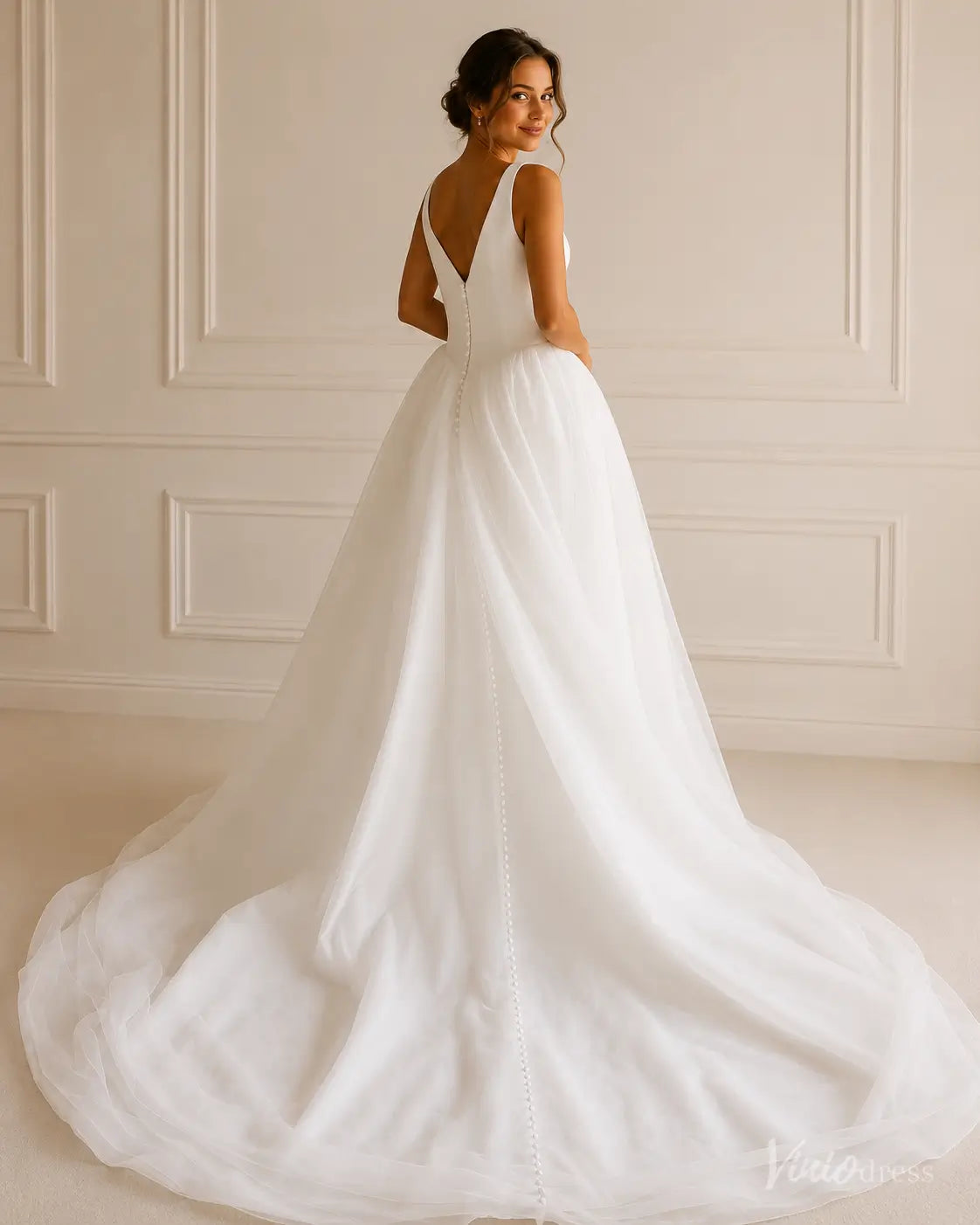 White A-line wedding dress with a V-neckline, sheer tulle skirt, and elegant button-down back detail.