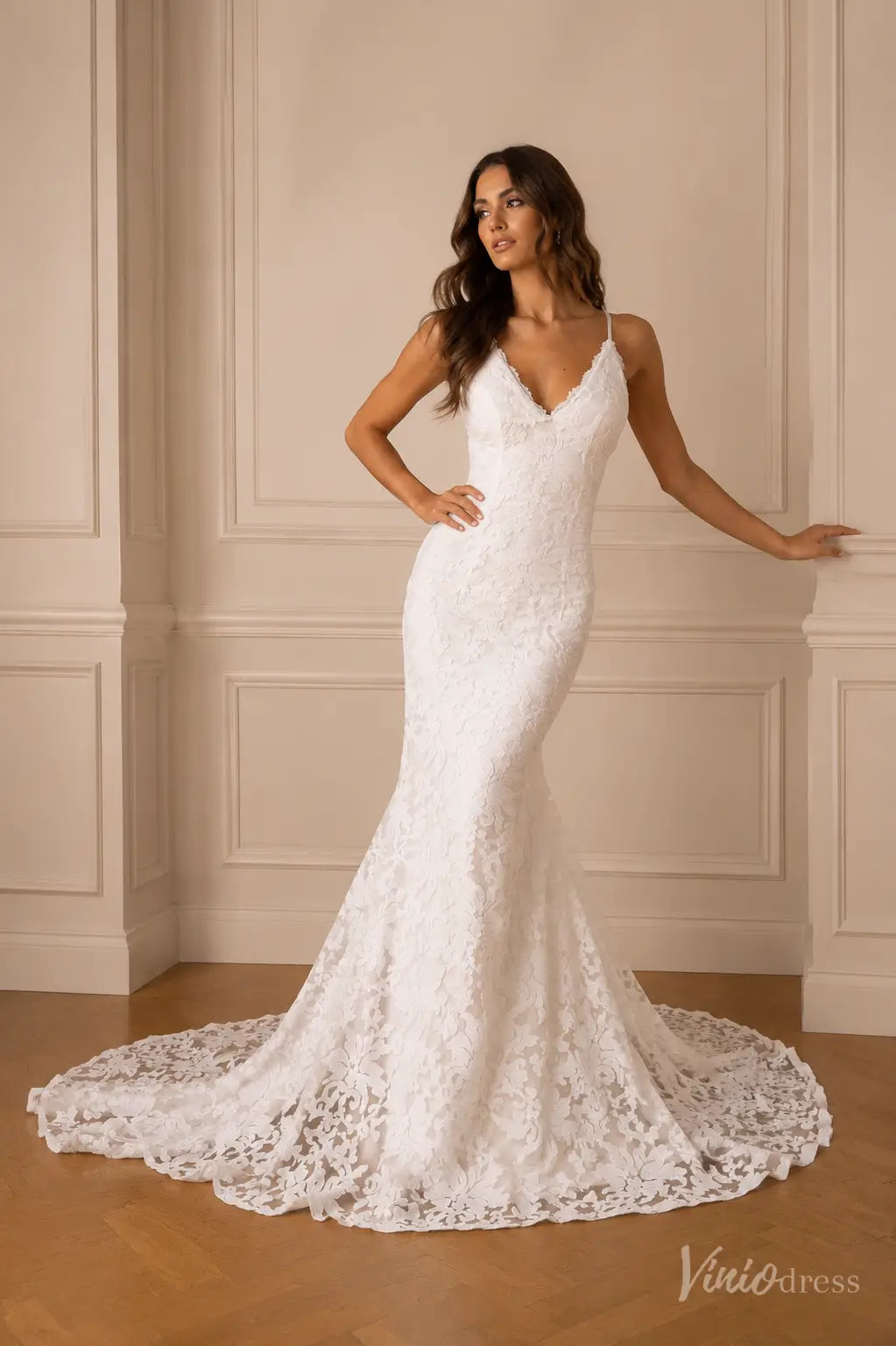 White lace mermaid wedding dress with a V-neckline, spaghetti straps, and a sweeping train.