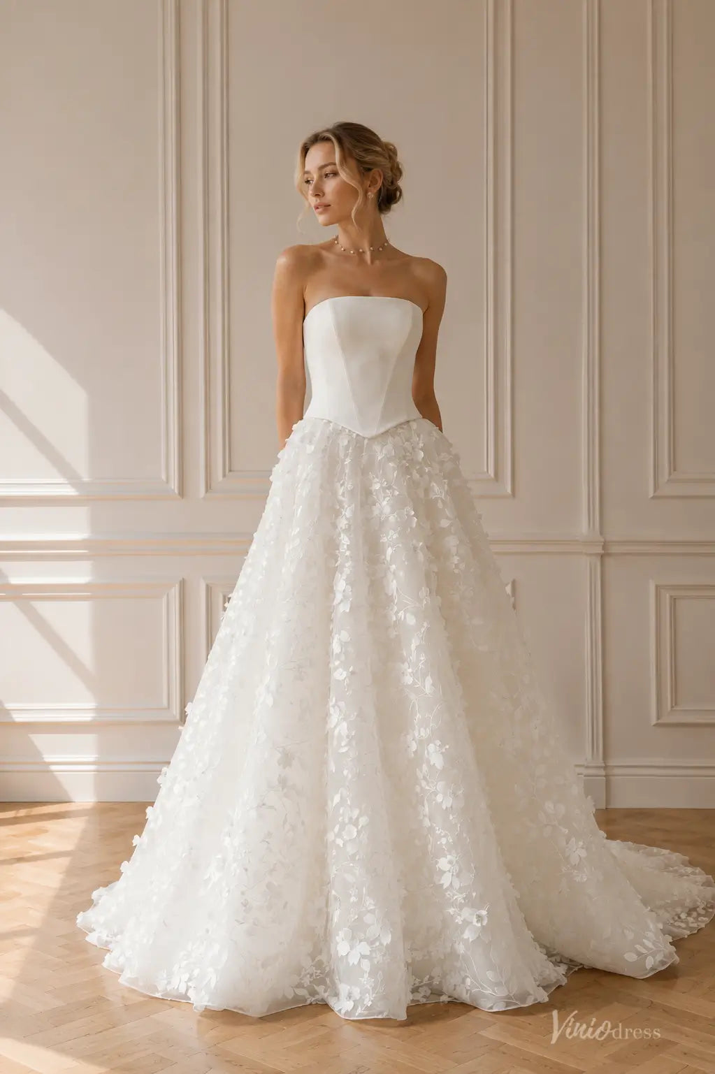 White strapless wedding dress with a structured corset bodice and a voluminous A-line skirt featuring 3D floral appliqués.