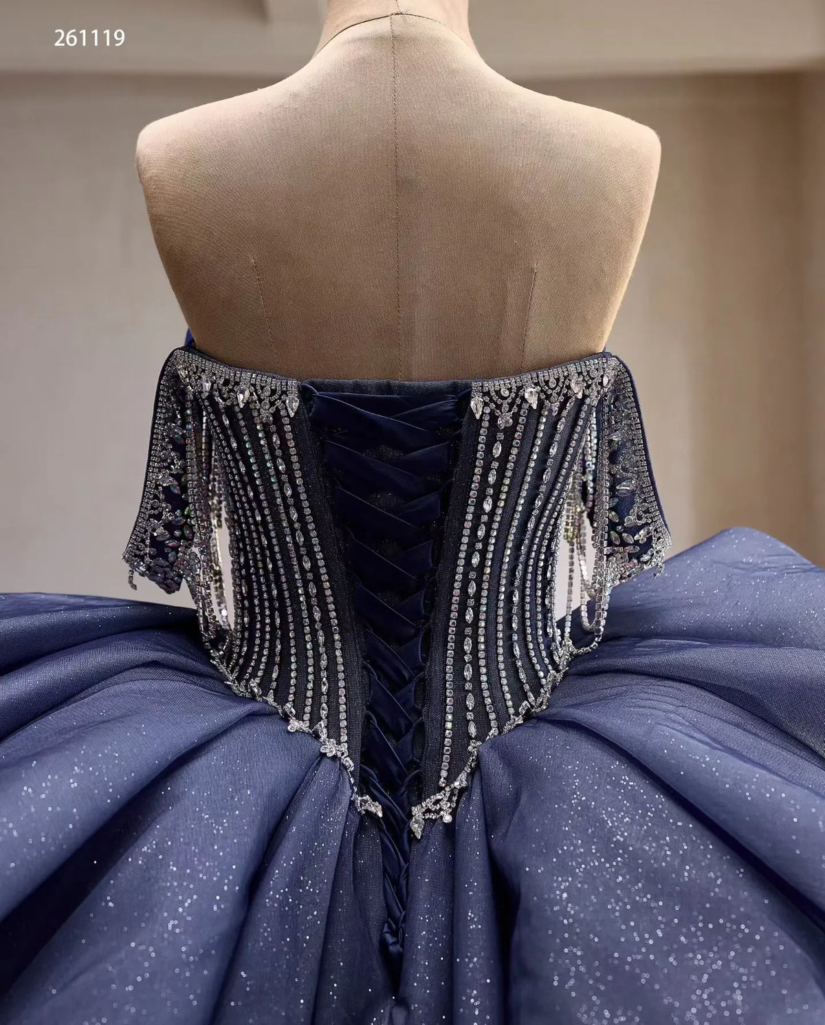 Dusty blue quinceañera dress with a crystal-draped corset, lace-up back, and shimmering voluminous skirt.