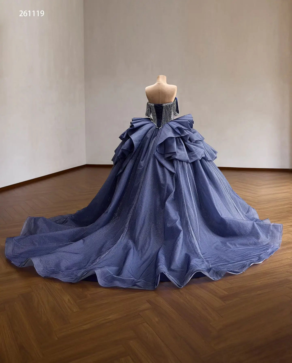 Dusty blue quinceañera dress with crystal corset, off-shoulder straps, and a voluminous ruffled skirt with a long train.