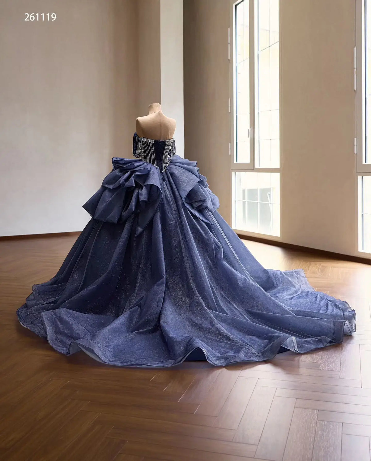 Dusty blue quinceañera dress with a crystal-draped corset, off-shoulder straps, and a voluminous ruffled skirt.
