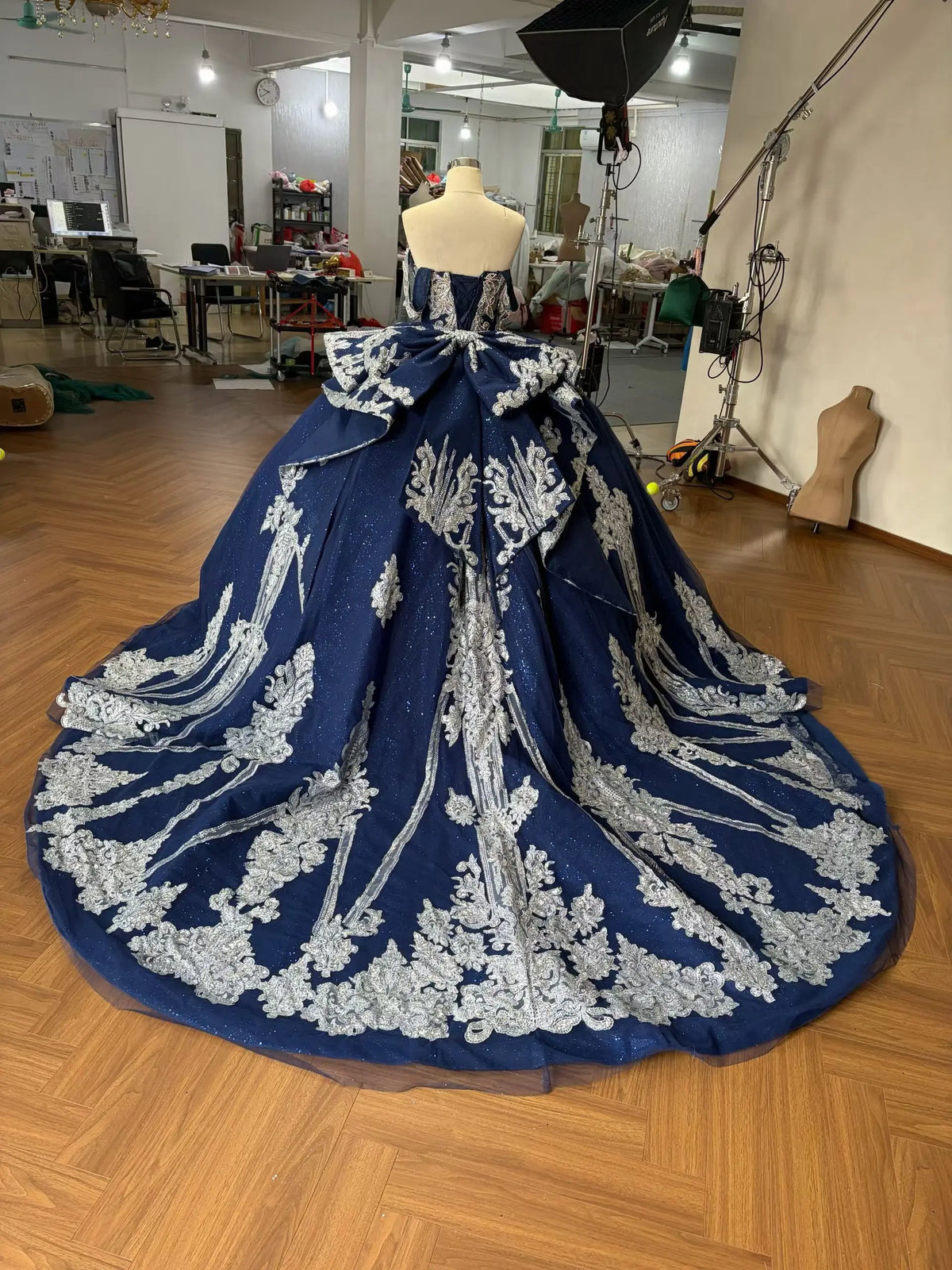 Navy blue ball gown with silver baroque embroidery, crystal corset, and a dramatic cathedral train on a mannequin.