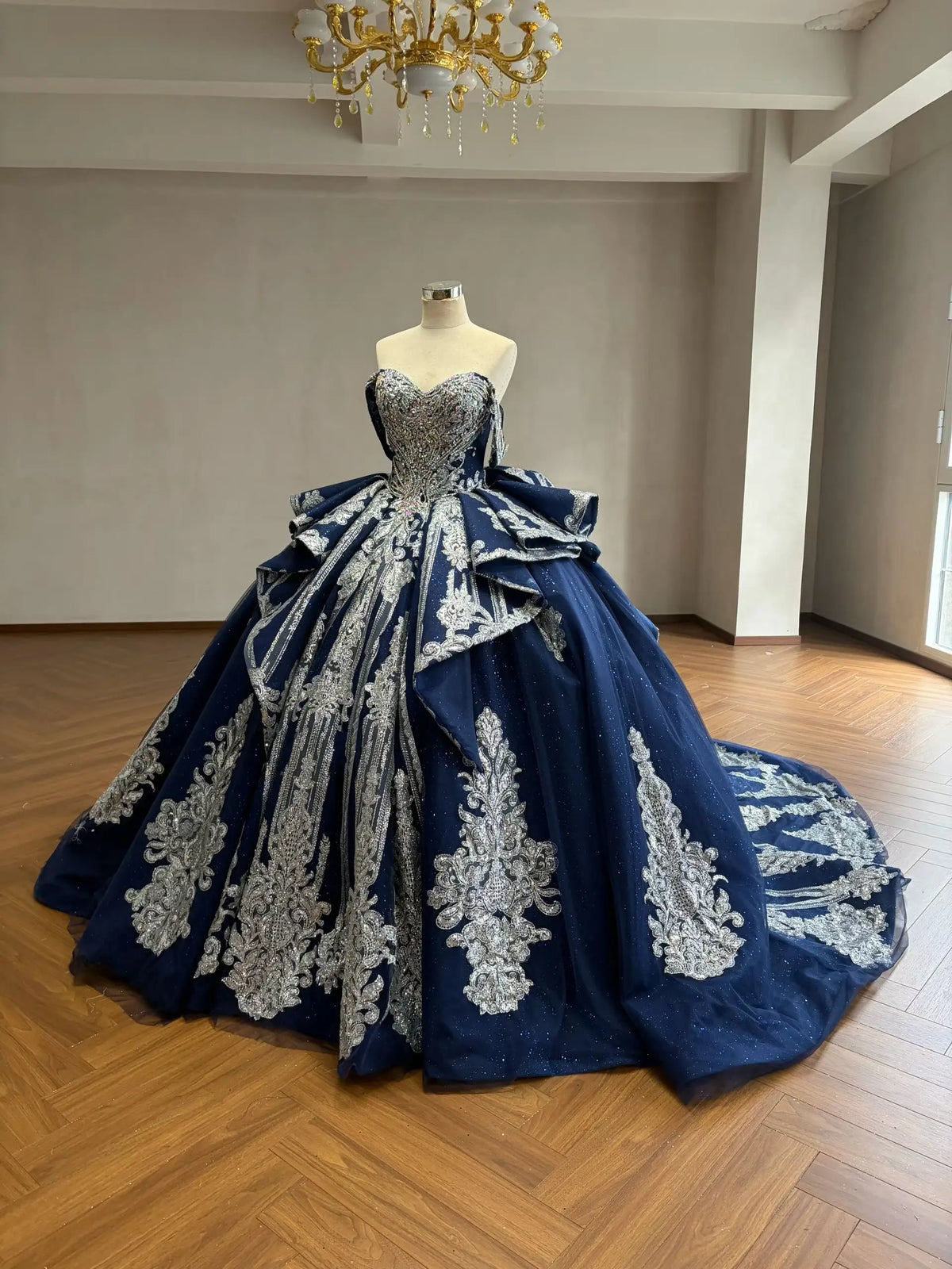 Navy blue quinceañera ball gown with silver baroque embroidery, crystal corset, and a dramatic cathedral train.