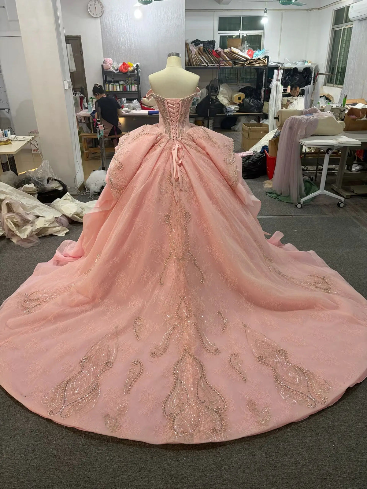 Pink quinceañera dress with crystal corset, oversized back bow, and embroidered full skirt with lace-up back.