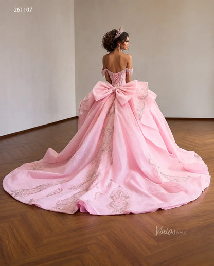 Pink quinceañera dress with crystal corset, oversized back bow, layered overskirt, and ornate silver embroidery.