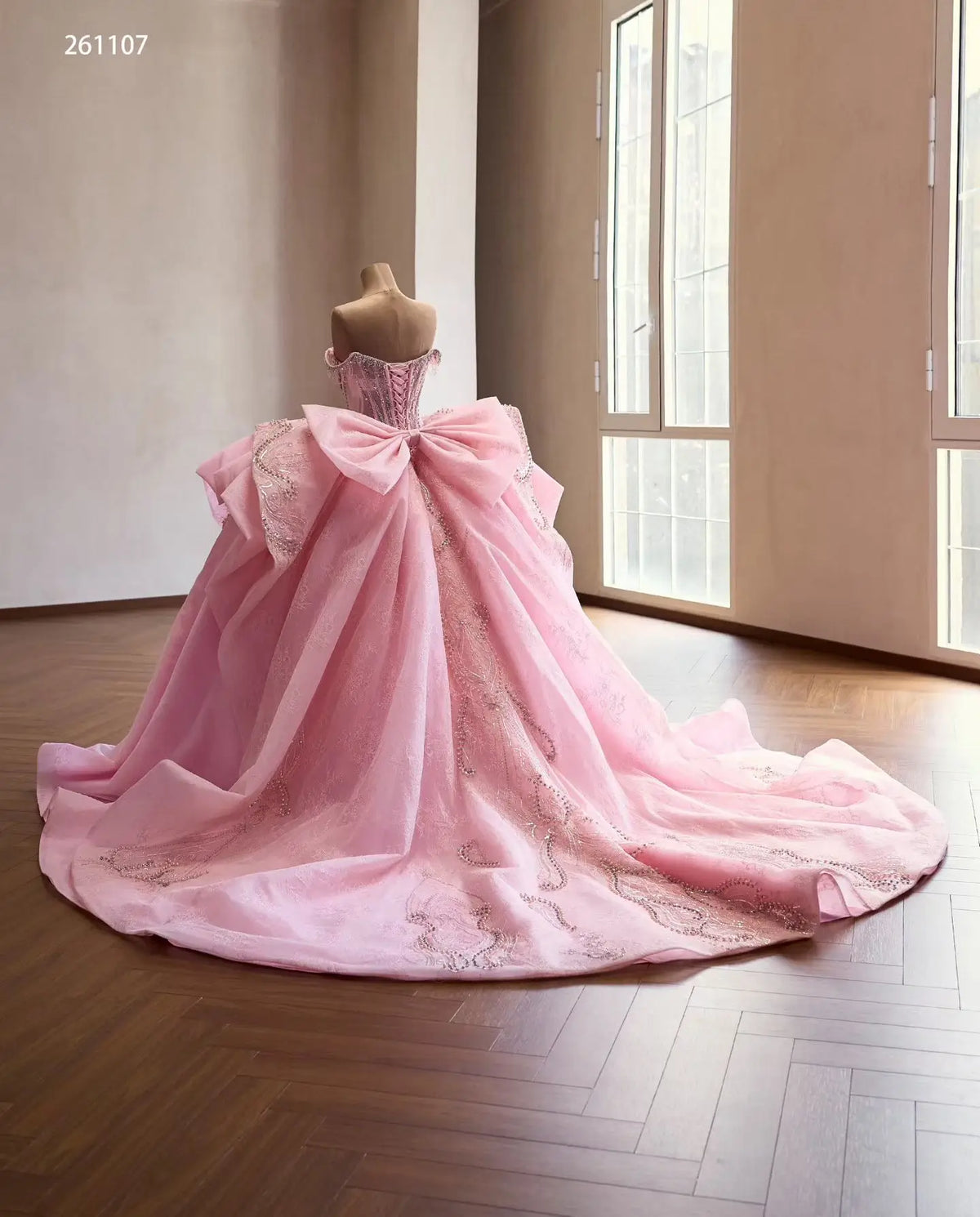Pink quinceañera dress with crystal corset, oversized back bow, and full embroidered skirt with layered overskirt.