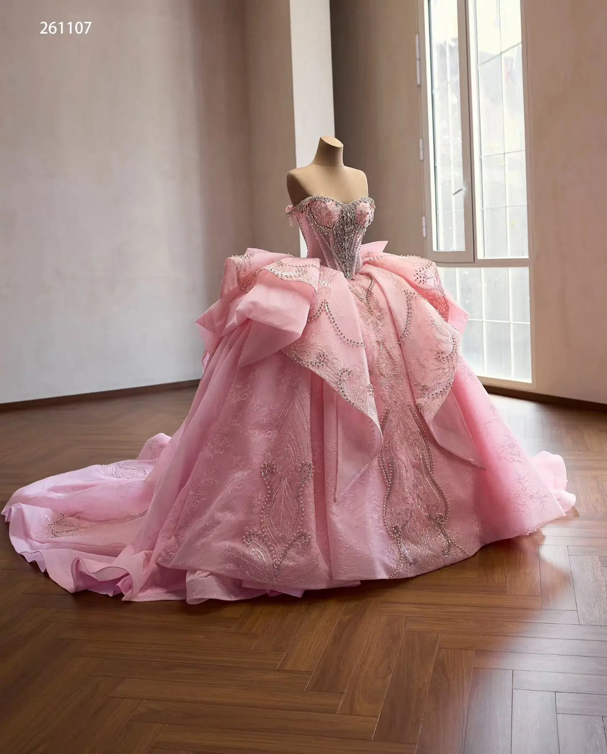 Pink off-shoulder quinceañera dress with crystal corset, sculptural layered overskirt, and ornate beaded embroidery.